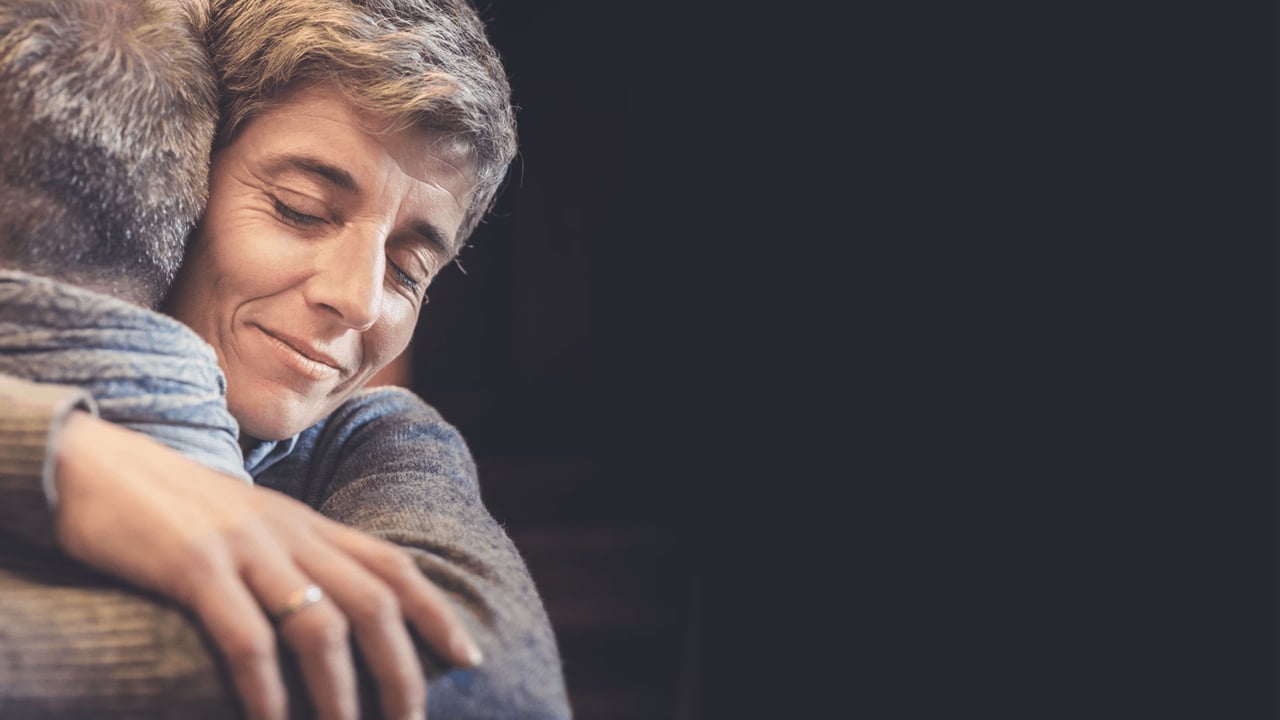 Close-up of adult woman, eyes closed, warmly embracing her partner